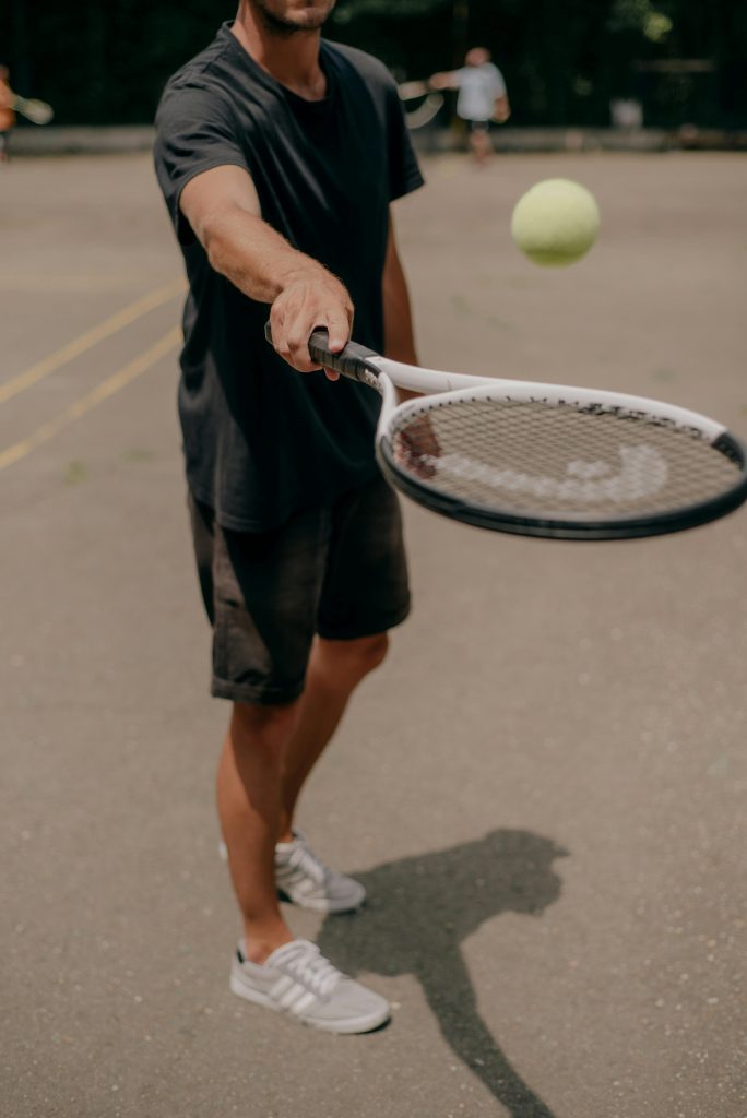 Adult male tennis player practicing serve with racket on outdoor court.